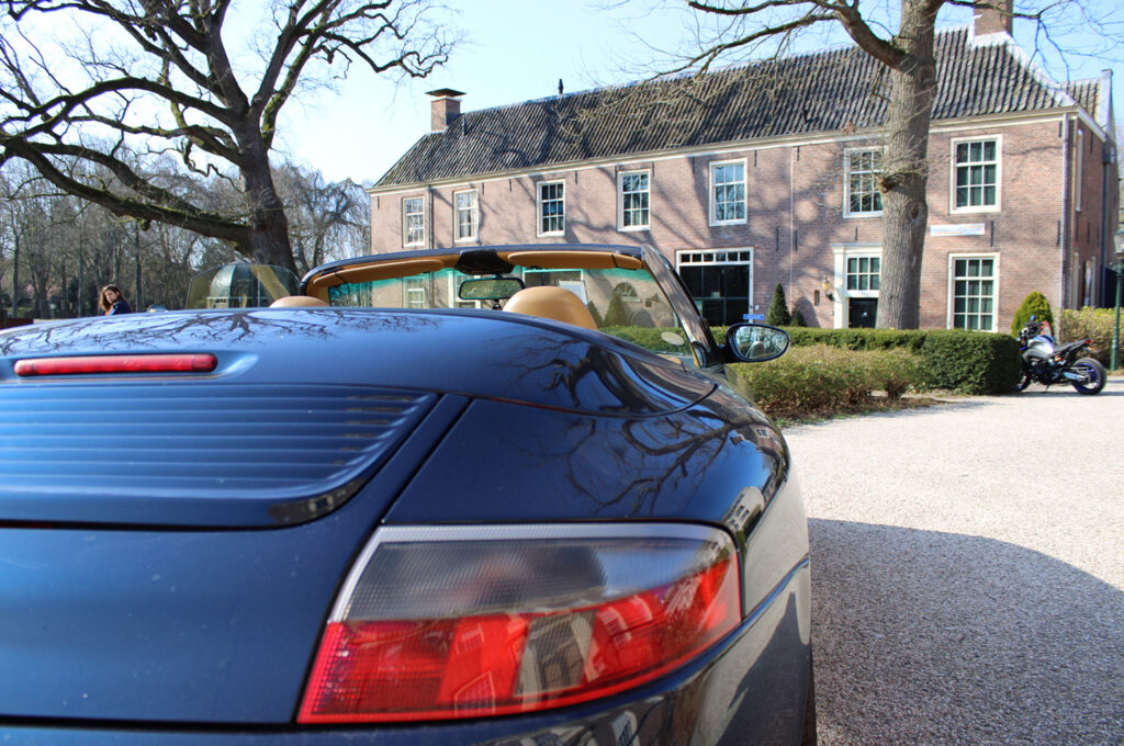 Blauwe Porsche 911 Cabriolet geparkeerd voor een huis