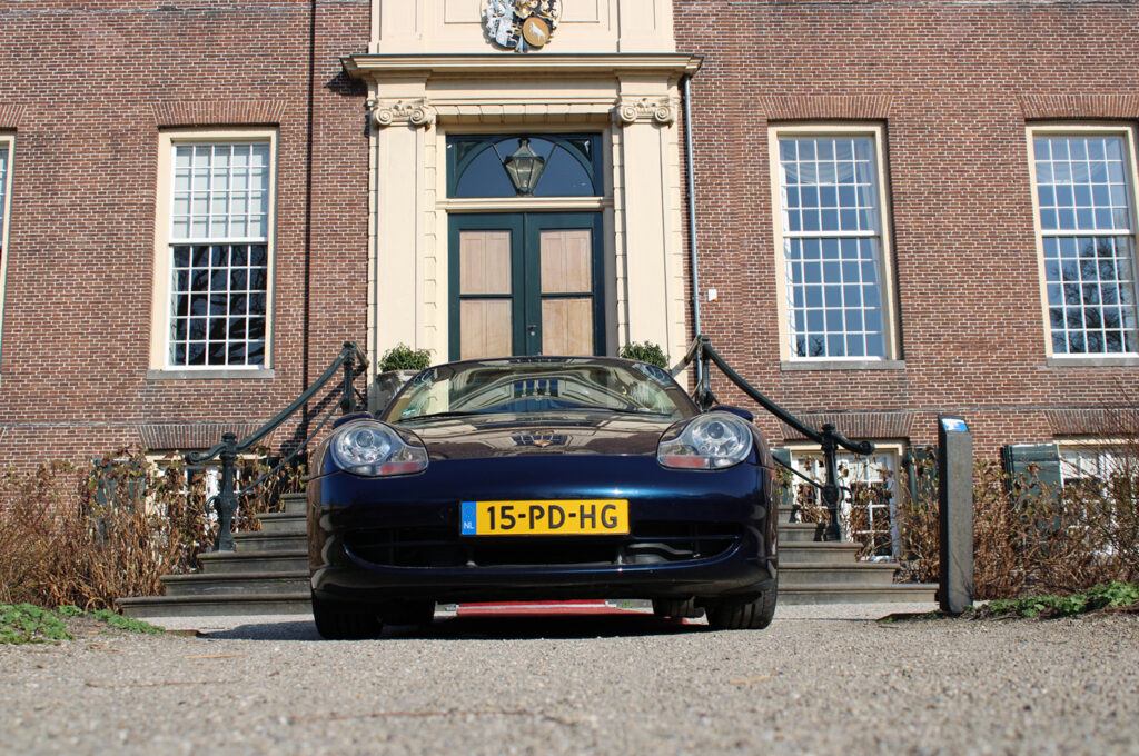 Blauwe Porsche 911 met Nederlands kenteken voor historisch huis in Nederland